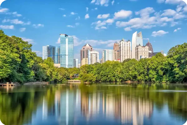 Atlanta GA skyline with trees and water reflection under blue sky