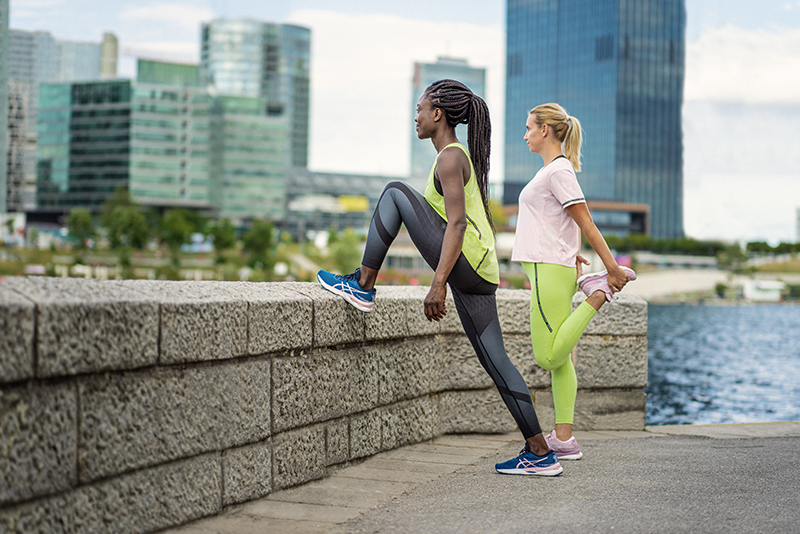 Two women outside stretching wearing the nimbus 24