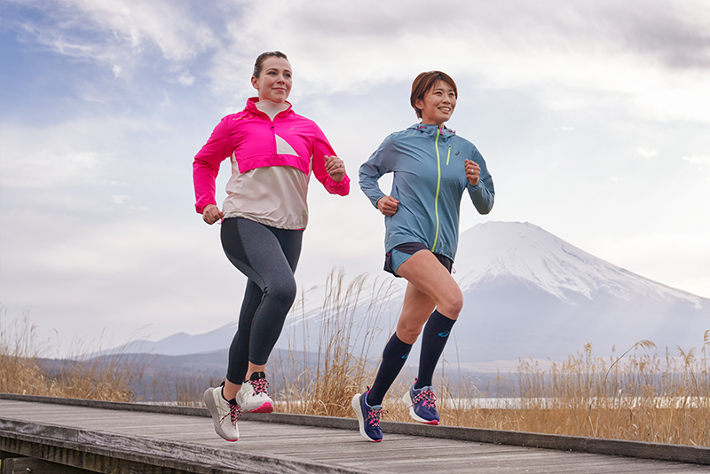 Two runners running in bright pink and blue jackets