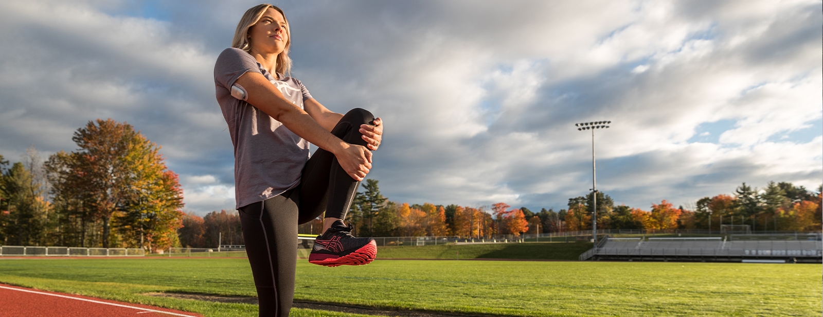 Runner stretching on field in asics shoes