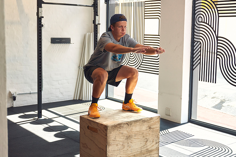 Man doing squat jump onto a box