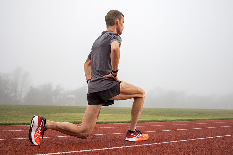 Man doing a leg stretch outside on a track