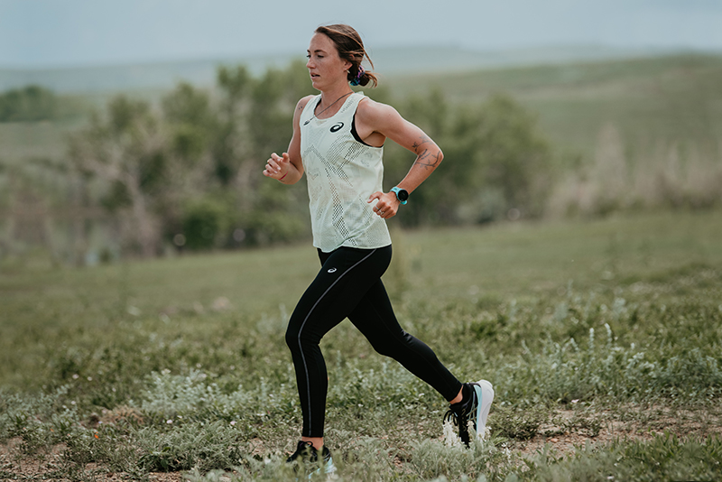 ASICS woman athlete running outside on a road trail