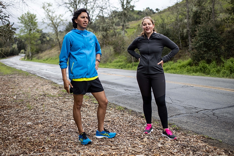 Man and woman in sporty gear standing outdoor.