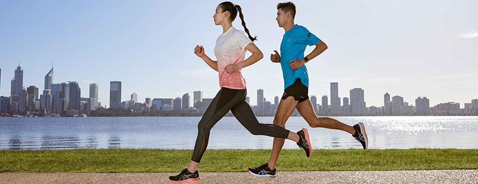 Man and women running outside along the water in a city