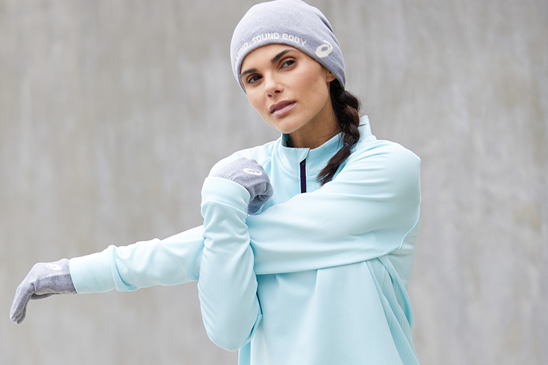 One runner stretching wearing a hat and matching gloves