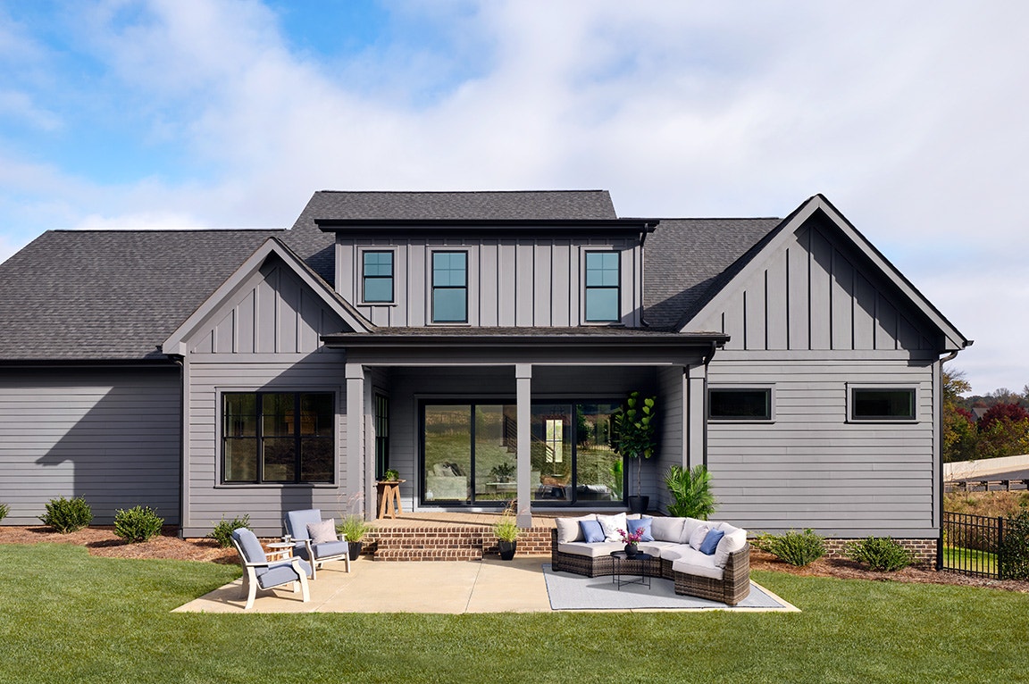 Large glass patio doors on a gray modern home with outdoor seating and a covered porch.