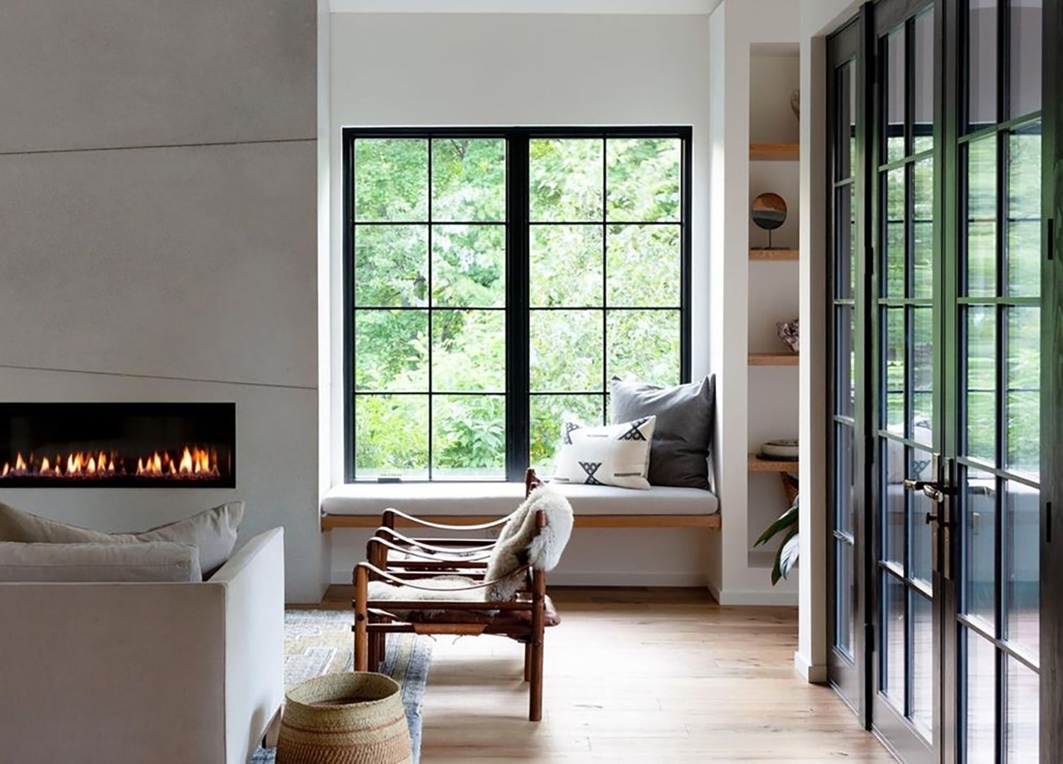 Two black casement windows open the living room to fresh air and offer seating area to warm up by the fireplace.