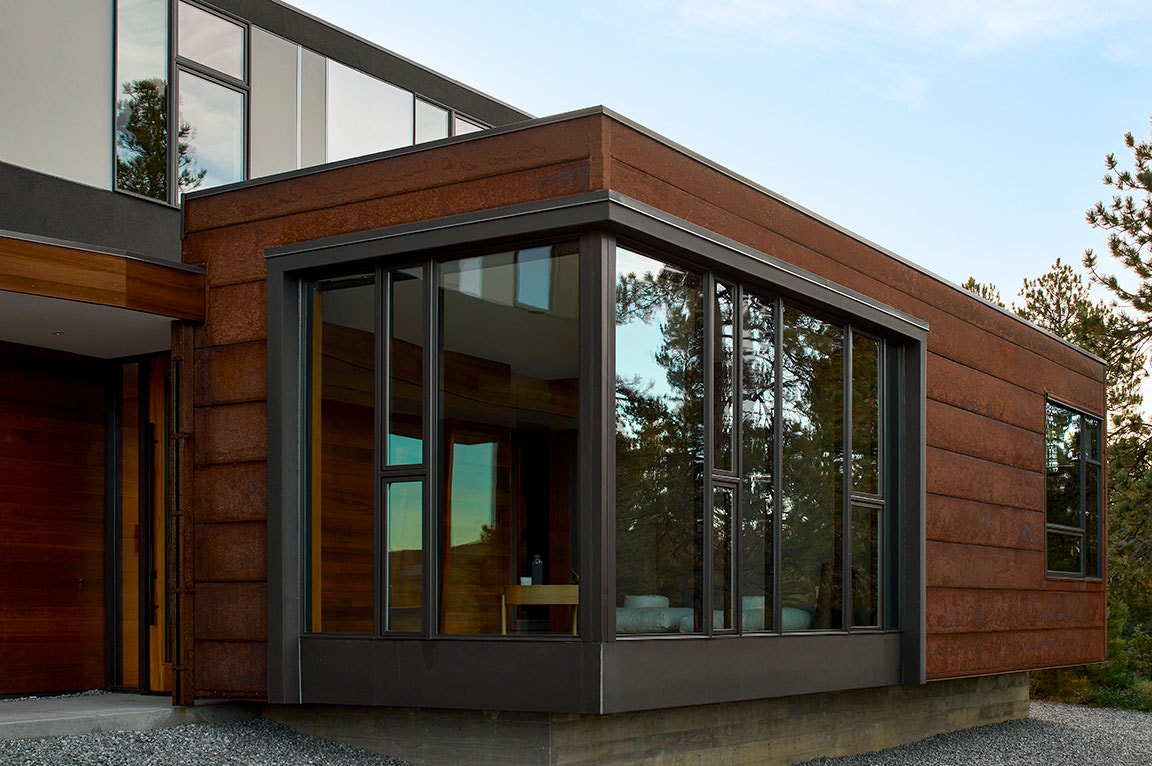 A modern home exterior featuring large brown windows and a sleek design.