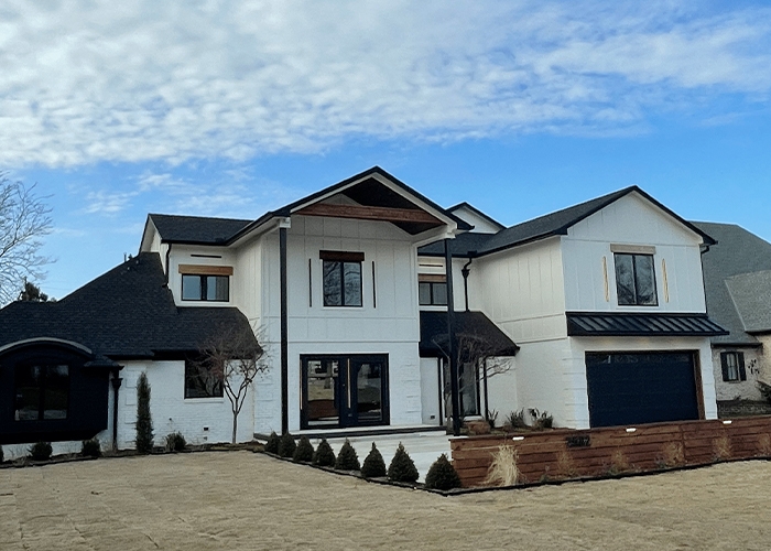 An Oklahoma area home exterior after a major renovation, featuring black windows and doors and white siding