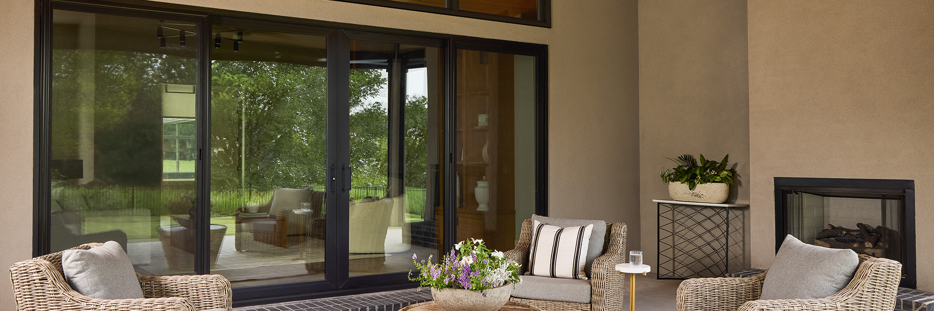 A black sliding patio door that offers a seamless connection to to a deck with patio furniture. 