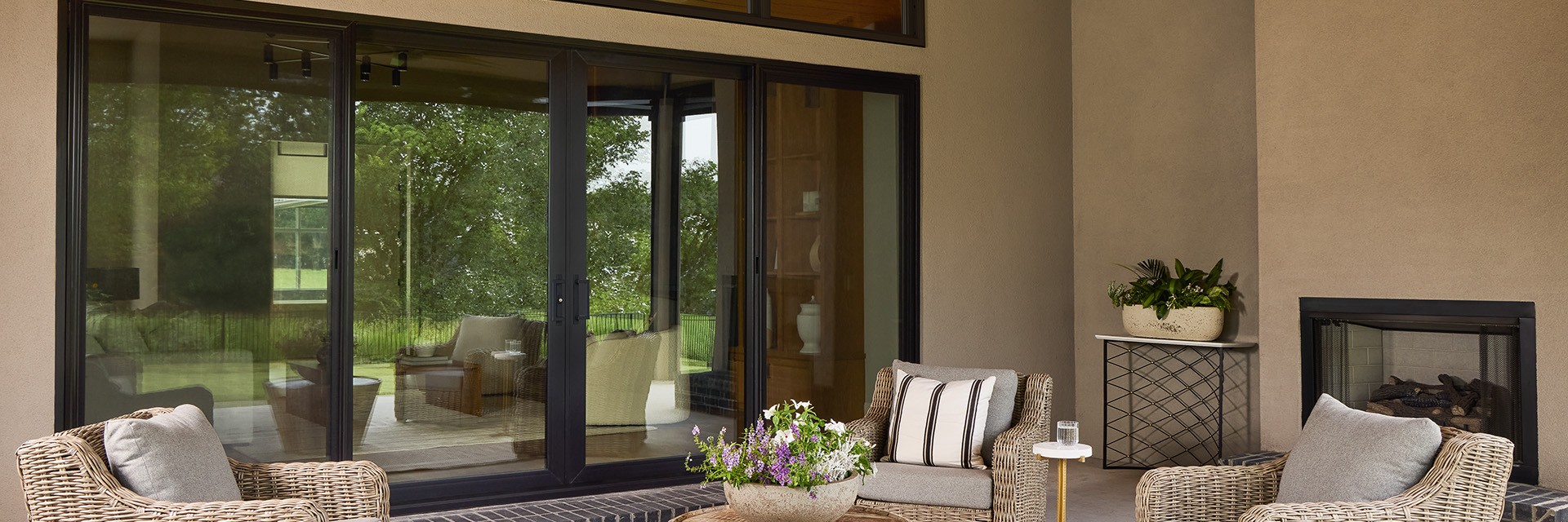 A black sliding patio door that offers a seamless connection to to a deck with patio furniture.
