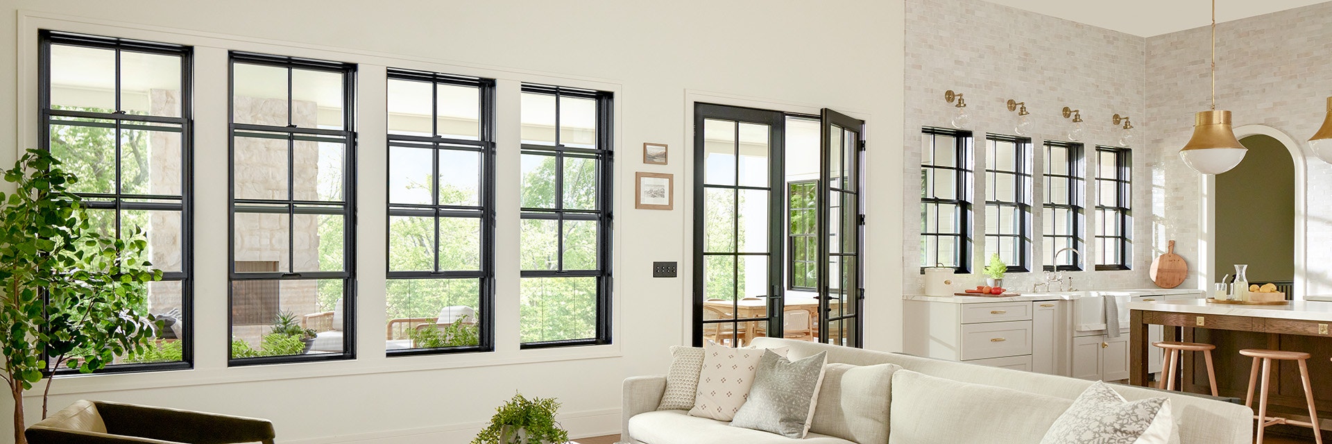 Open floor plan living room and kitchen with black double-hung windows and patio door.