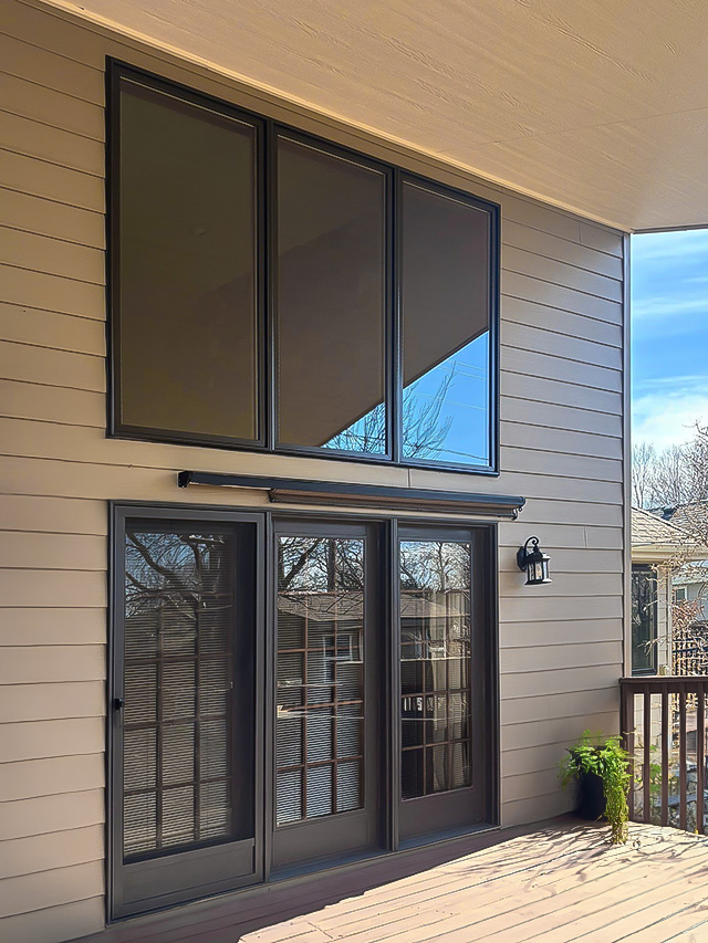 A modern home exterior showcasing large replacement windows and a wooden deck.