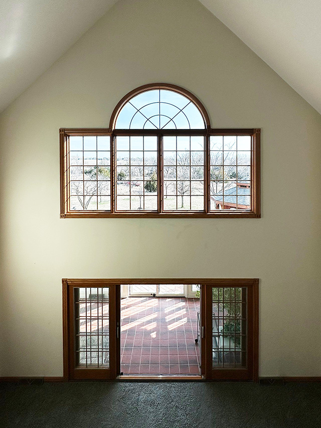 An arched window and large glass doors in a home interior, showcasing replacement windows.