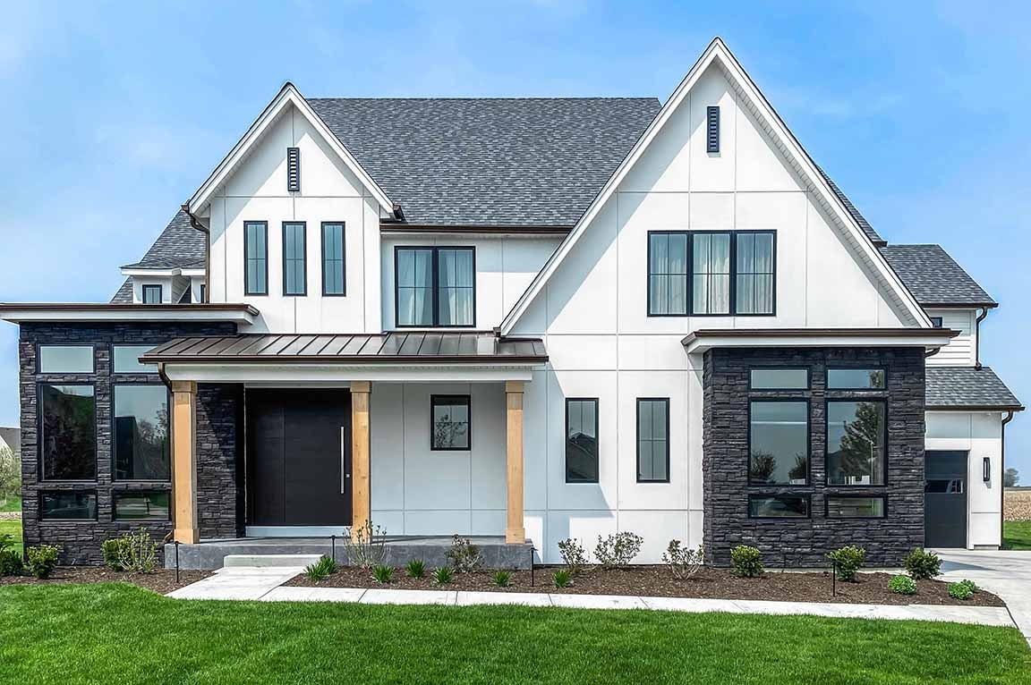 Modern farmhouse exterior with black windows, white siding, and stone accents.