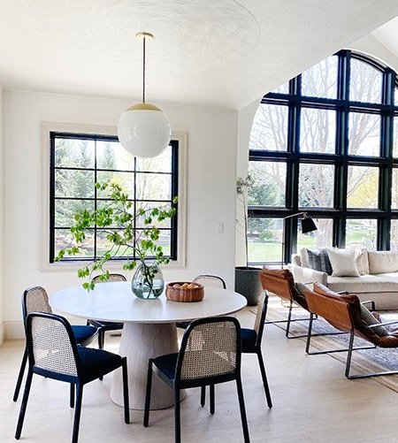 Breakfast nook with black window overlooking living room with large arched picture window