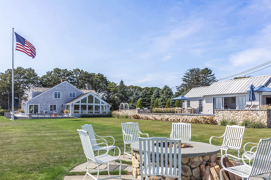 Coastal home with firepit and outdoor seating area on spacious lawn