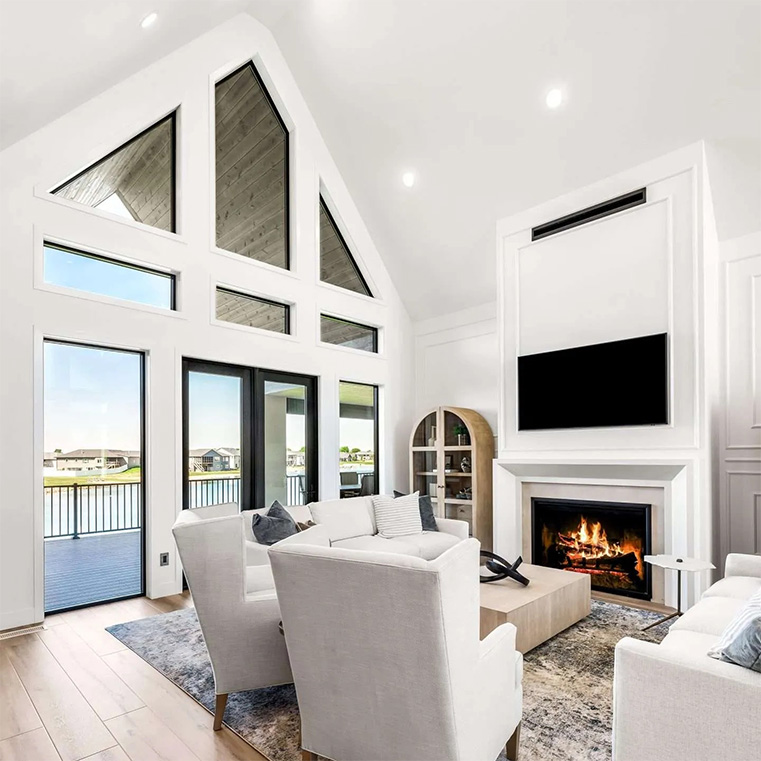 Modern living room with vaulted ceilings, large windows, and a fireplace with built-in TV.