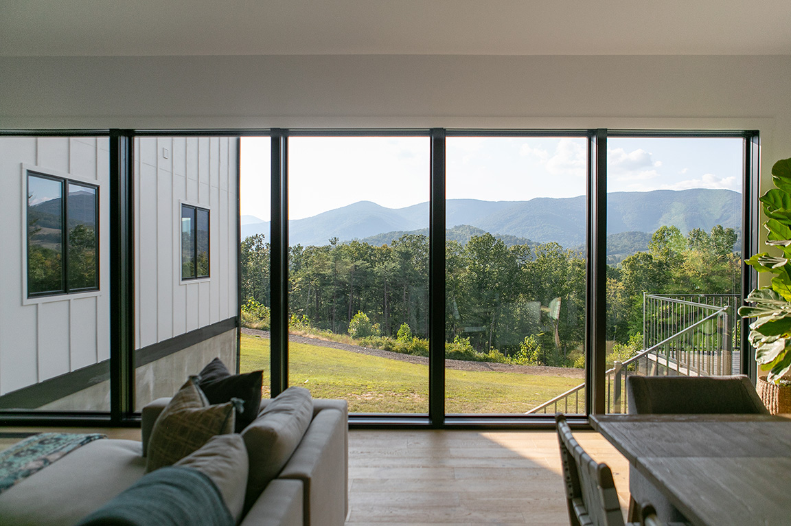 Interior view of floor-to-ceiling window wall framing Virginia mountains.