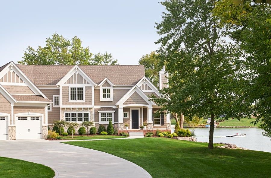 Exterior of tan two-story home with white double hung windows and a two car garage