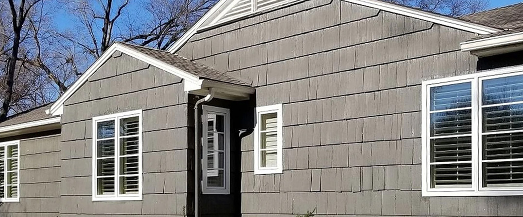 three sets of casement windows along the side of a wood-sided home in Kansas