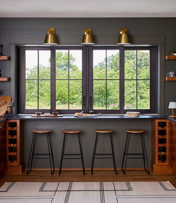Four barstools at a counter that sits level with a four-panel multi-slide window