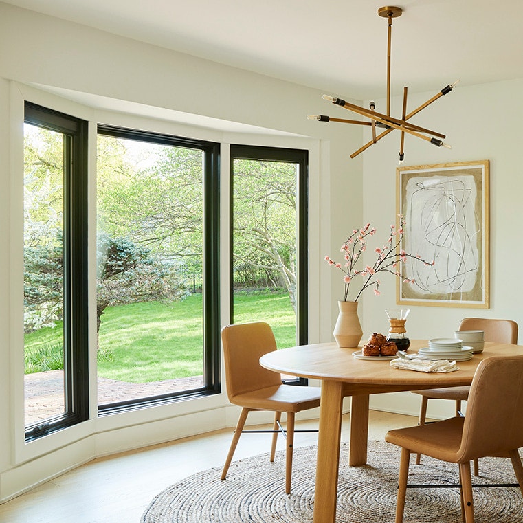 Mid-century modern dining room featuring three large windows.