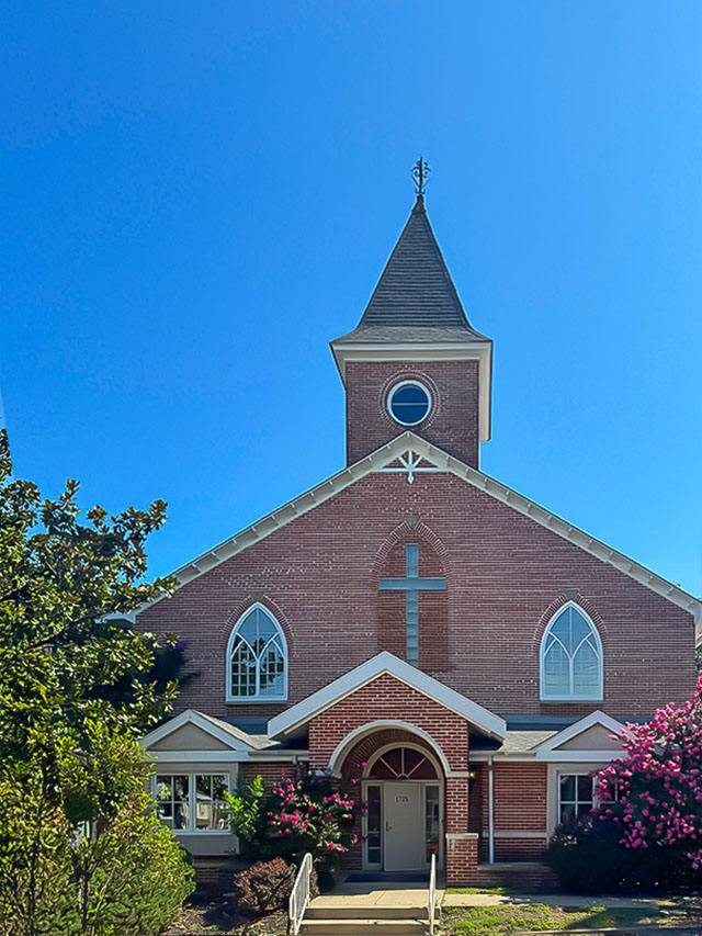 Red brick church with a tall steeple and arched windows in the West End Neighborhood House Little Italy.