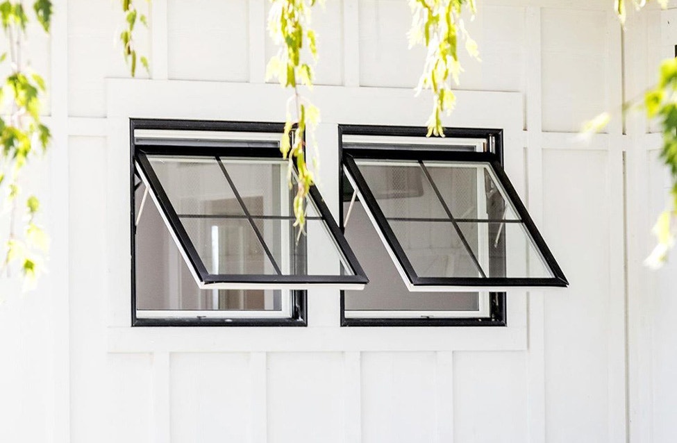 two contemporary awning windows with black trim that are open to the exterior