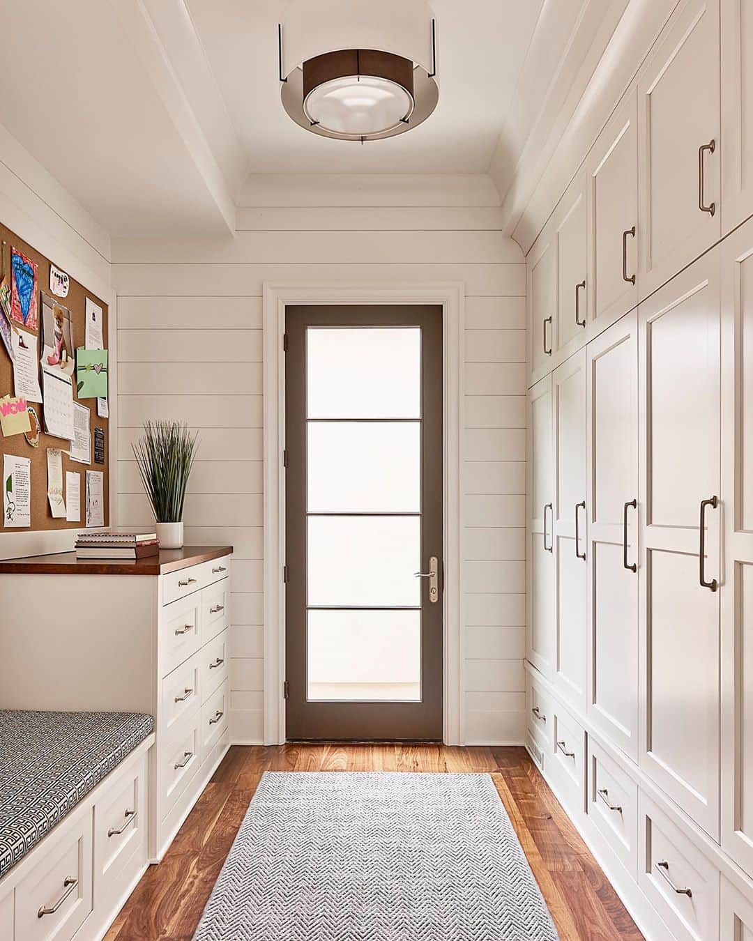 contemporary style mudroom with a wall of white cabinets leading to hinged glass patio door