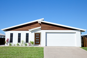 A simple white contemporary house with a four-light wood front door and white paint on the exterior walls of the home.