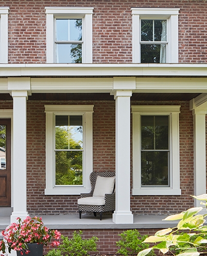 Exterior of a red brick home with replacement windows. 