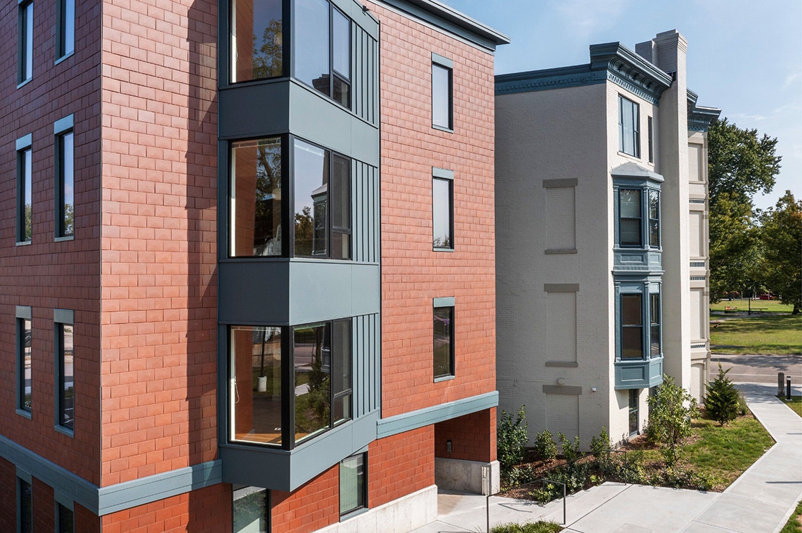 A modern apartment building exterior featuring black windows and a mix of brick and siding.