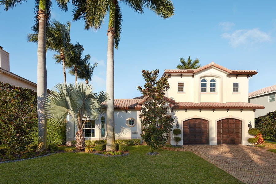 White home with white framed windows with grilles and palm trees