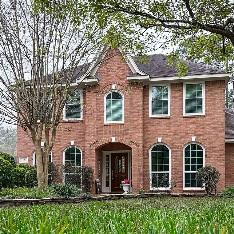 Houston Woodland Home with arched windows and red brick exterior.
