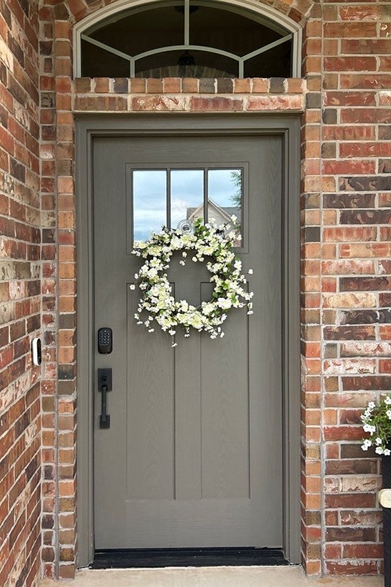 Before image of old tan front door on brick house. 