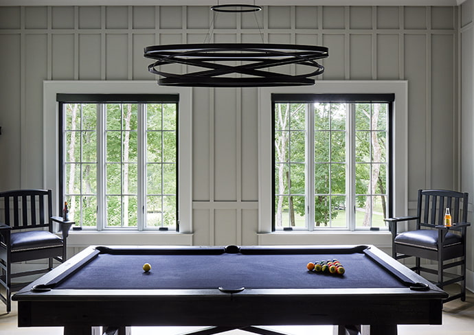 two sets of 3-wide wood windows behind a blue pool table