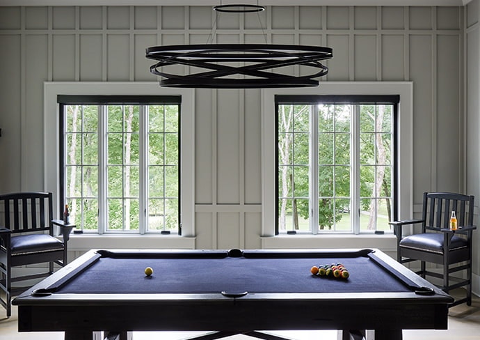 two sets of 3-wide wood windows behind a blue pool table