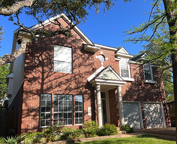 Outside view of a traditional brick home in Austin in need of new windows.