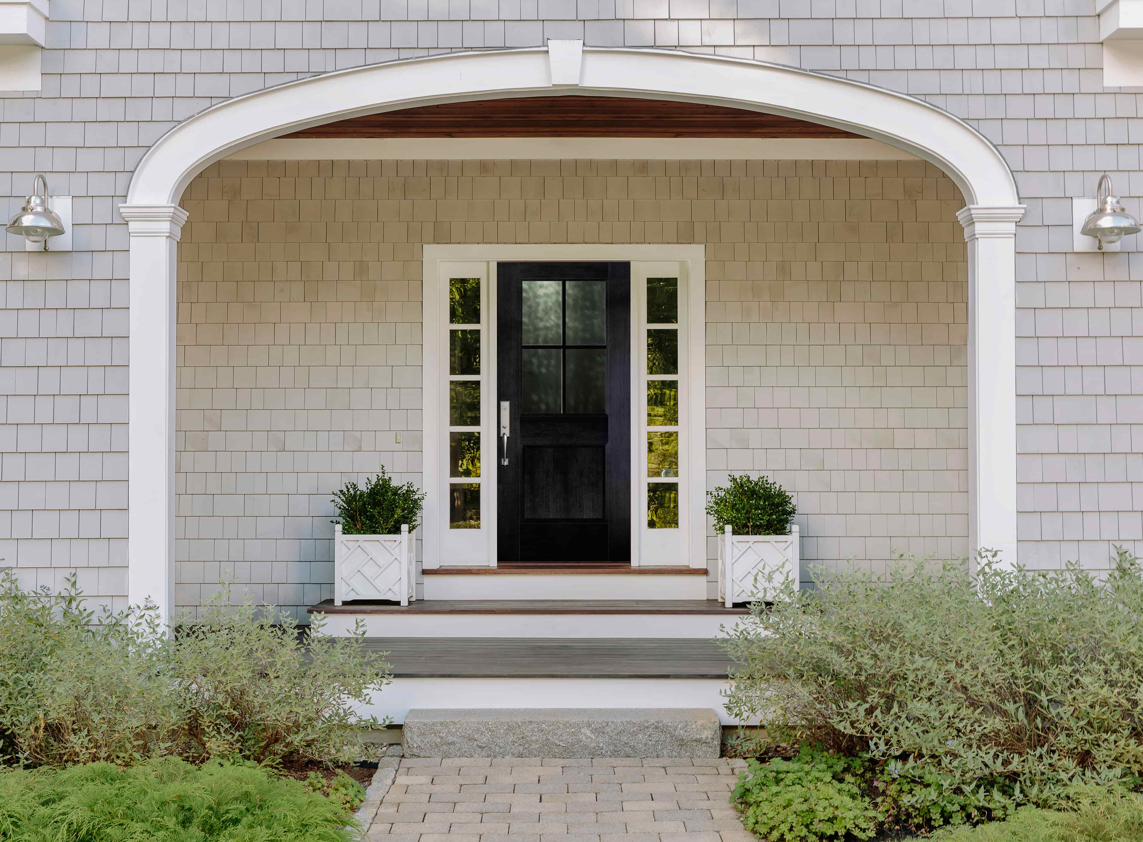 Black front door with white sidelights under arched farmhouse porch