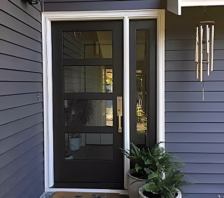 Modern black front door with four glass panels on blue house