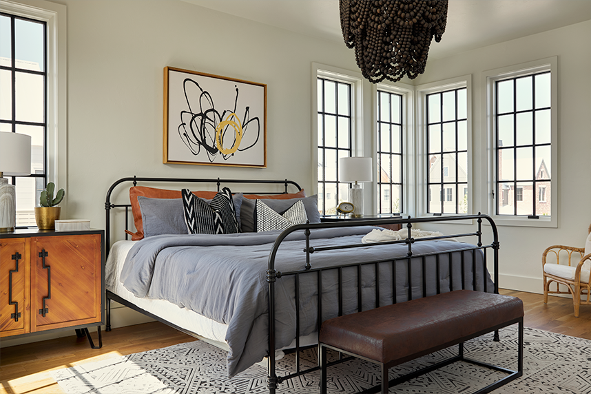Master bedroom with a king bed that has wrought iron framing and a contemporary painting on the wall above