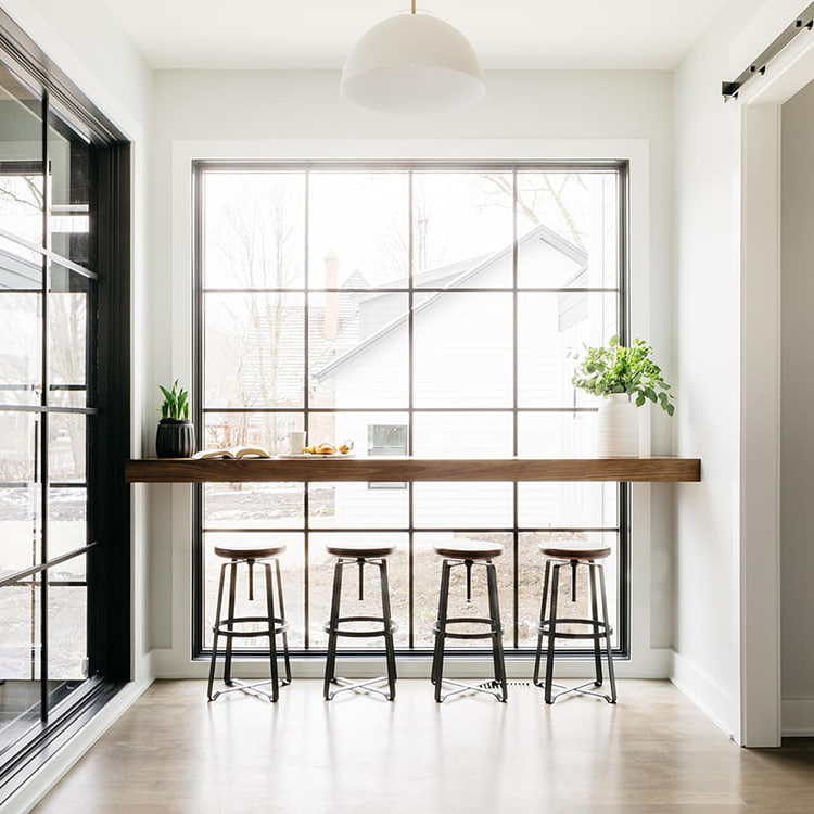 A bar with four barstools in front of an expansive floor-to-ceiling picture window.