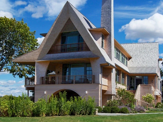 Backyard view of house with unique architecture with newly installed custom wood frame windows. 