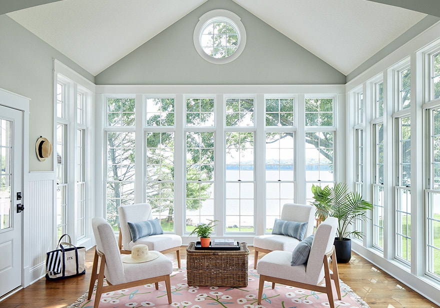 White single-hung windows in a sunroom with white chairs and an ocean view