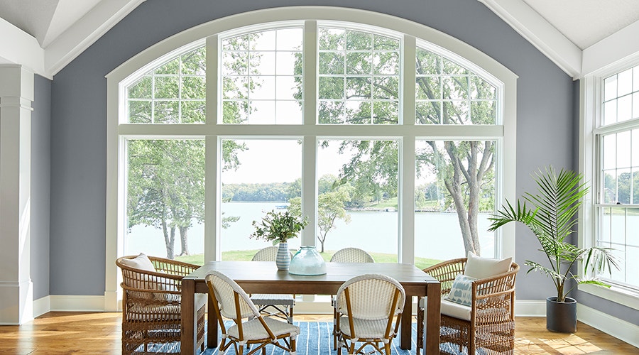 White arched frame windows that give a stunning view of a lake in the backyard.