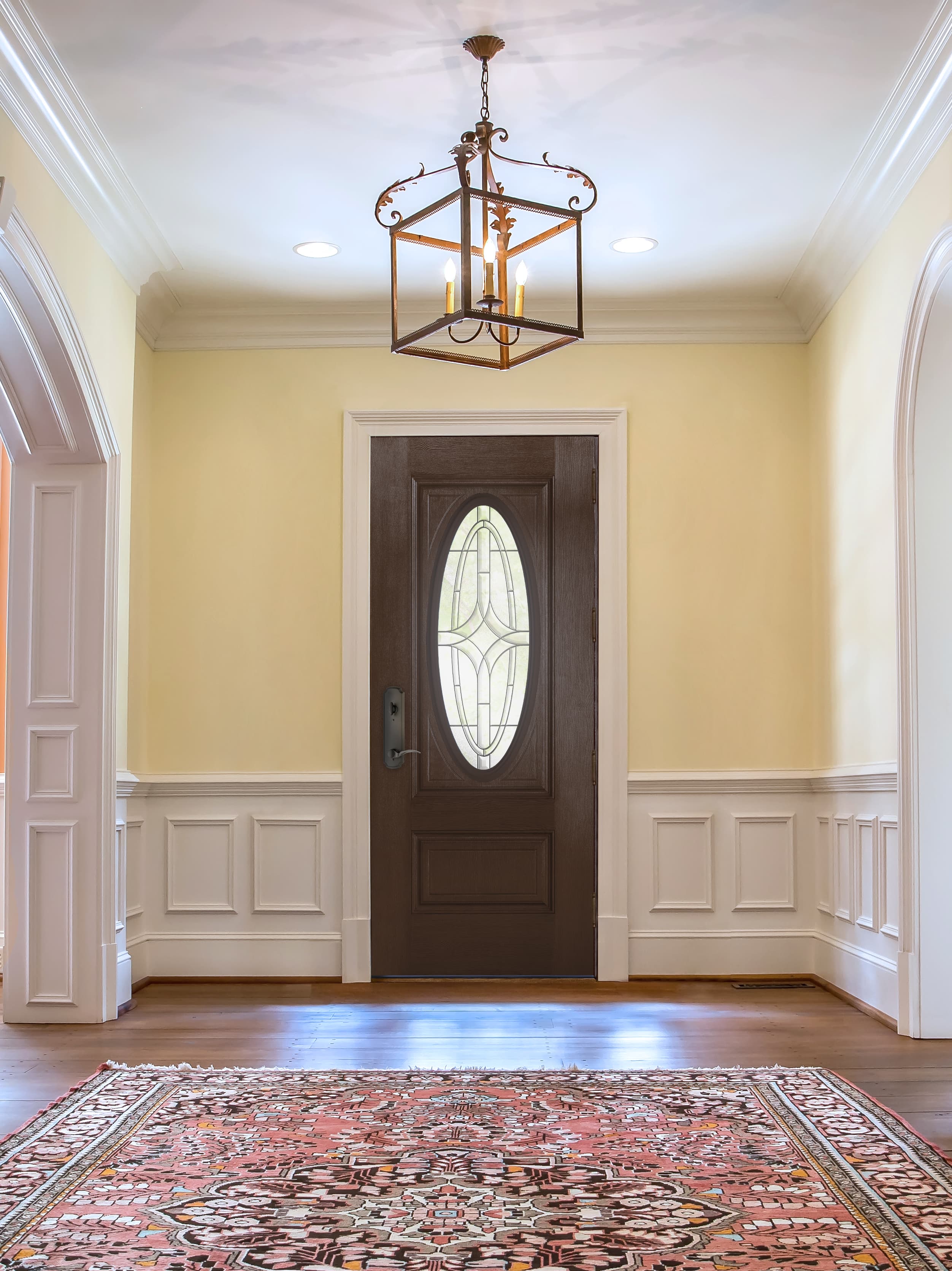 Brown front door with ornate glass in elegant entryway