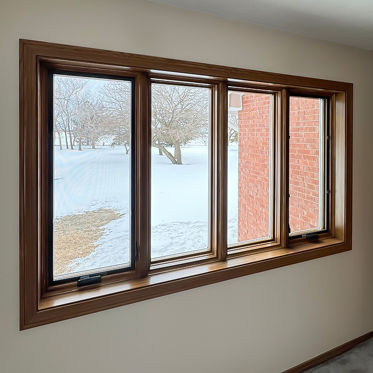 A set of casement windows with a white interior frames a snowy Kansas Valley Center view.