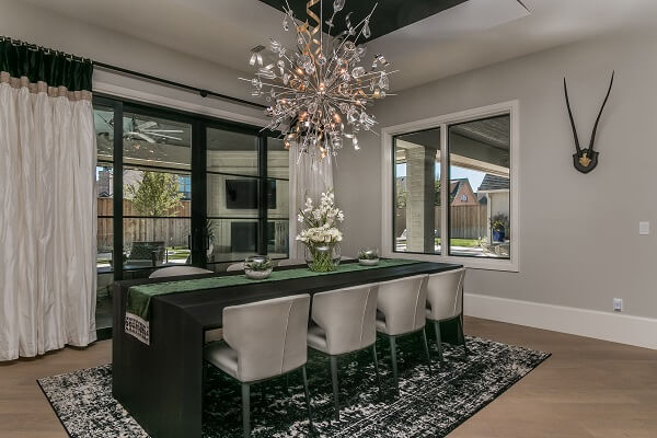 Modern dining room feature white casement windows, green table, and spiral metal chandelier